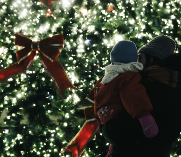 Un enfant et son parent qui regarde un arbre de Noël illuminé