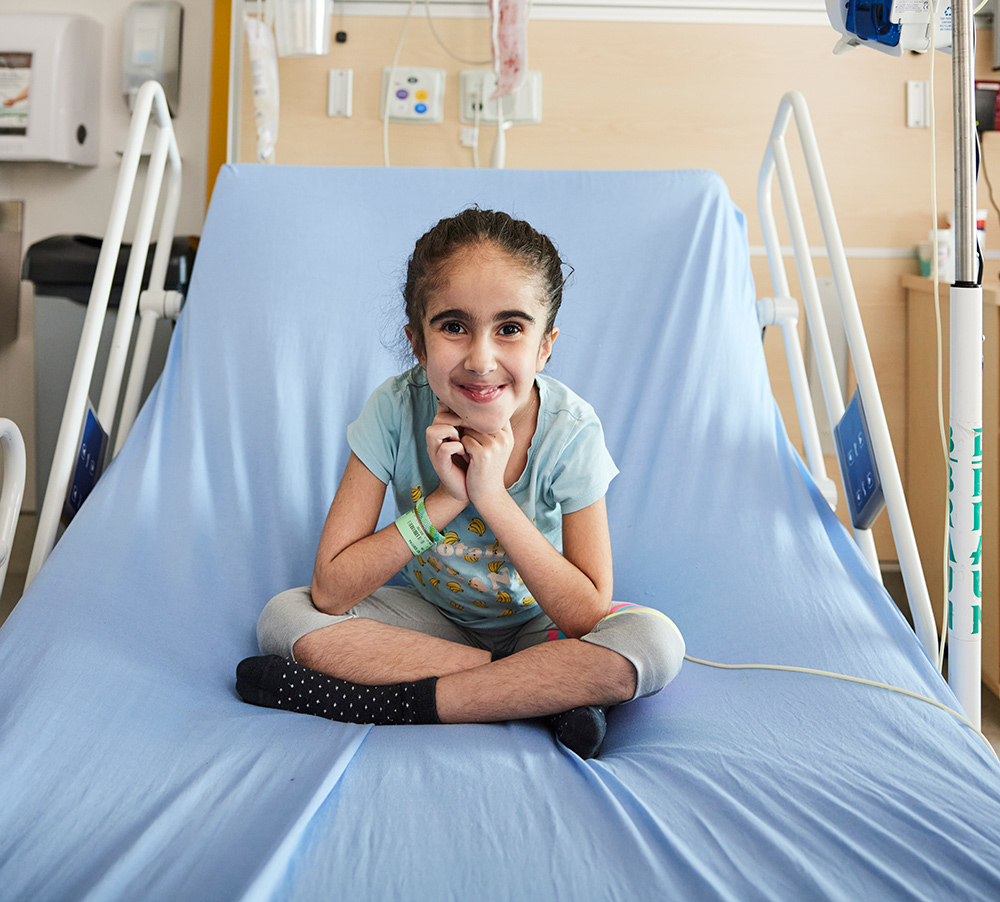 Petite fille espiègle assise dans un lit l'hôpital