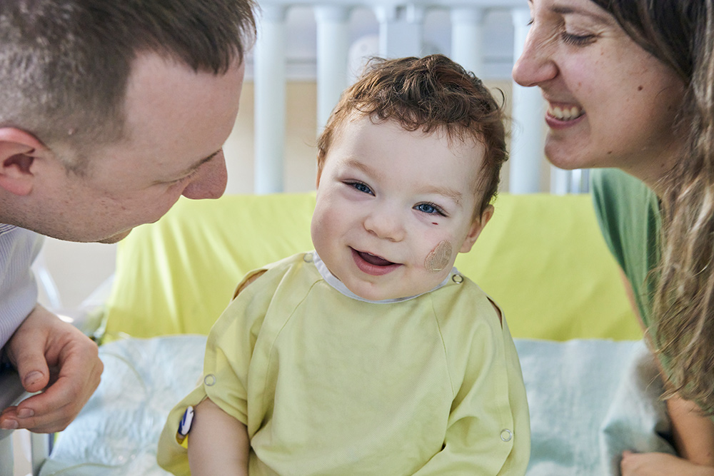 A smiling baby at the hospital with his parents