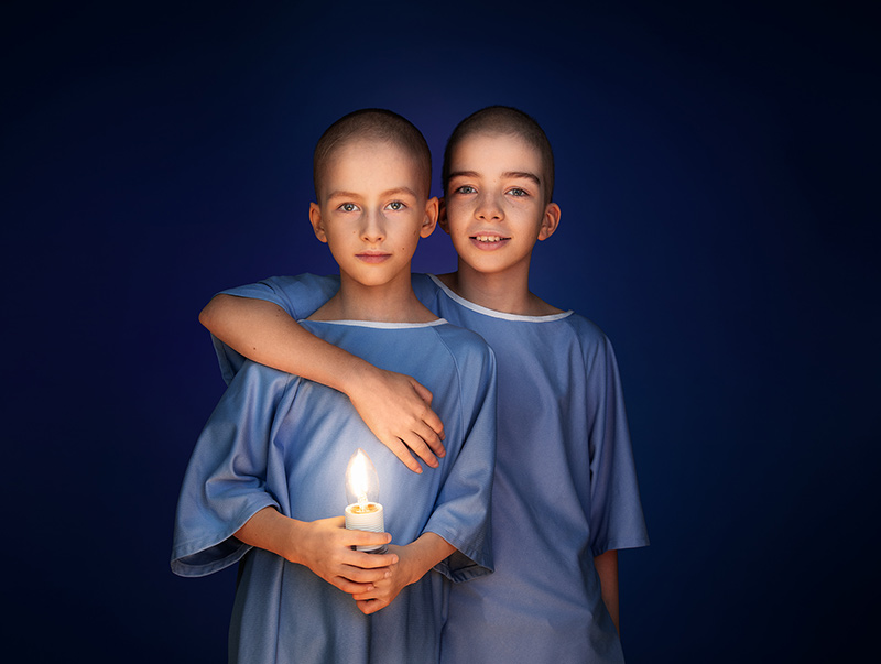 Jules et Lou, frère et sœur, sont vêtus d'une jaquette bleue, alors que Lou enlace Jules qui, lui, tient une ampoule allumée entre ses mains.
