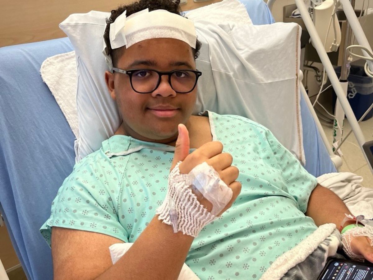 William lève le pouce en signe de victoire sur son lit d’hôpital, suite à son opération au cerveau.