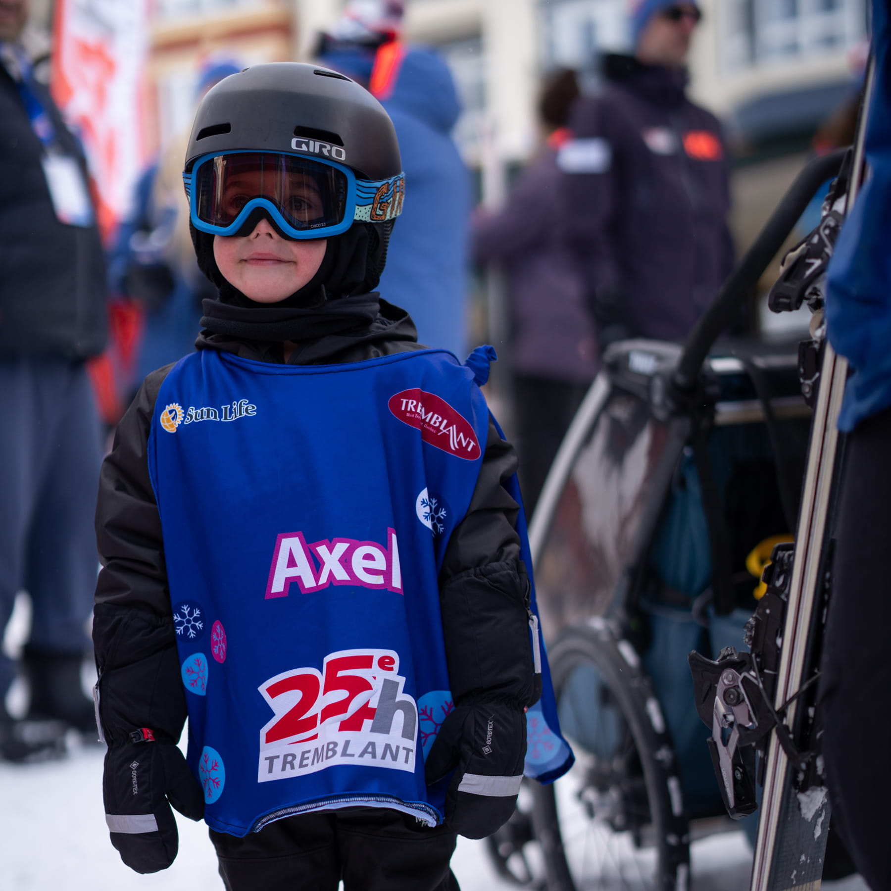 Un jeune garçon portant un habit de ski sourit. 