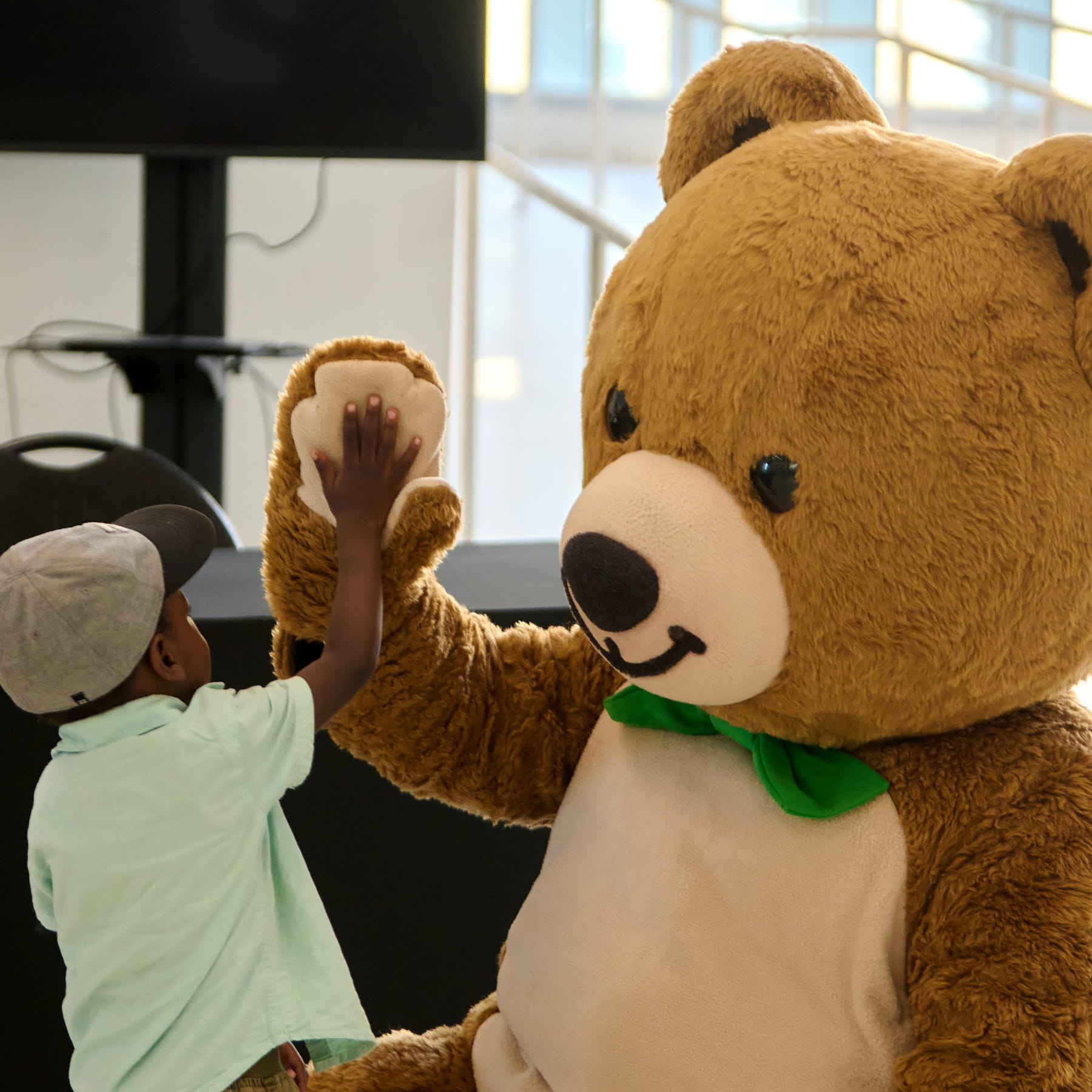 Une mascotte donne un « top là » à un petit garçon.