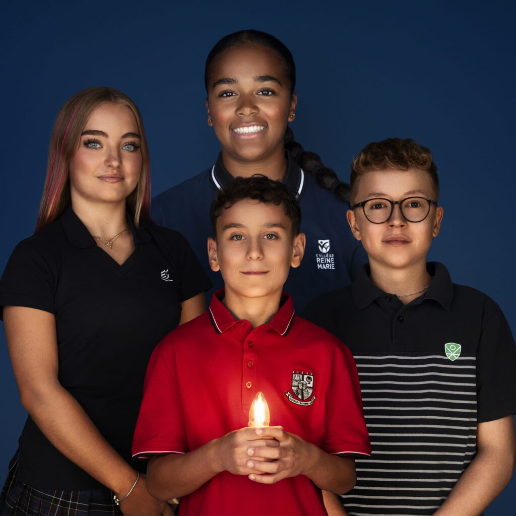 Un enfant tient une lumière, entouré de trois autres enfants 