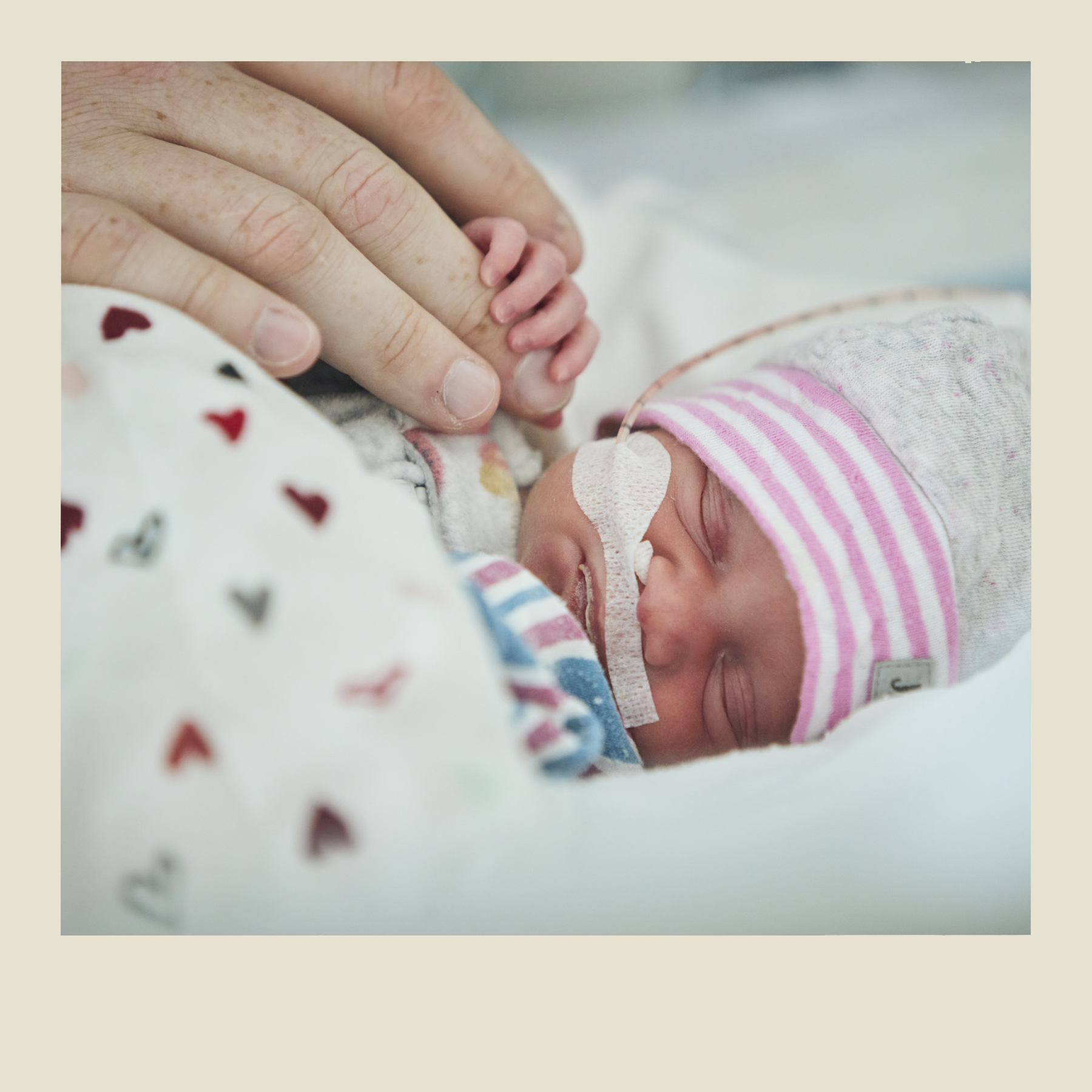 Un bébé prématuré tient la main d’un adulte.