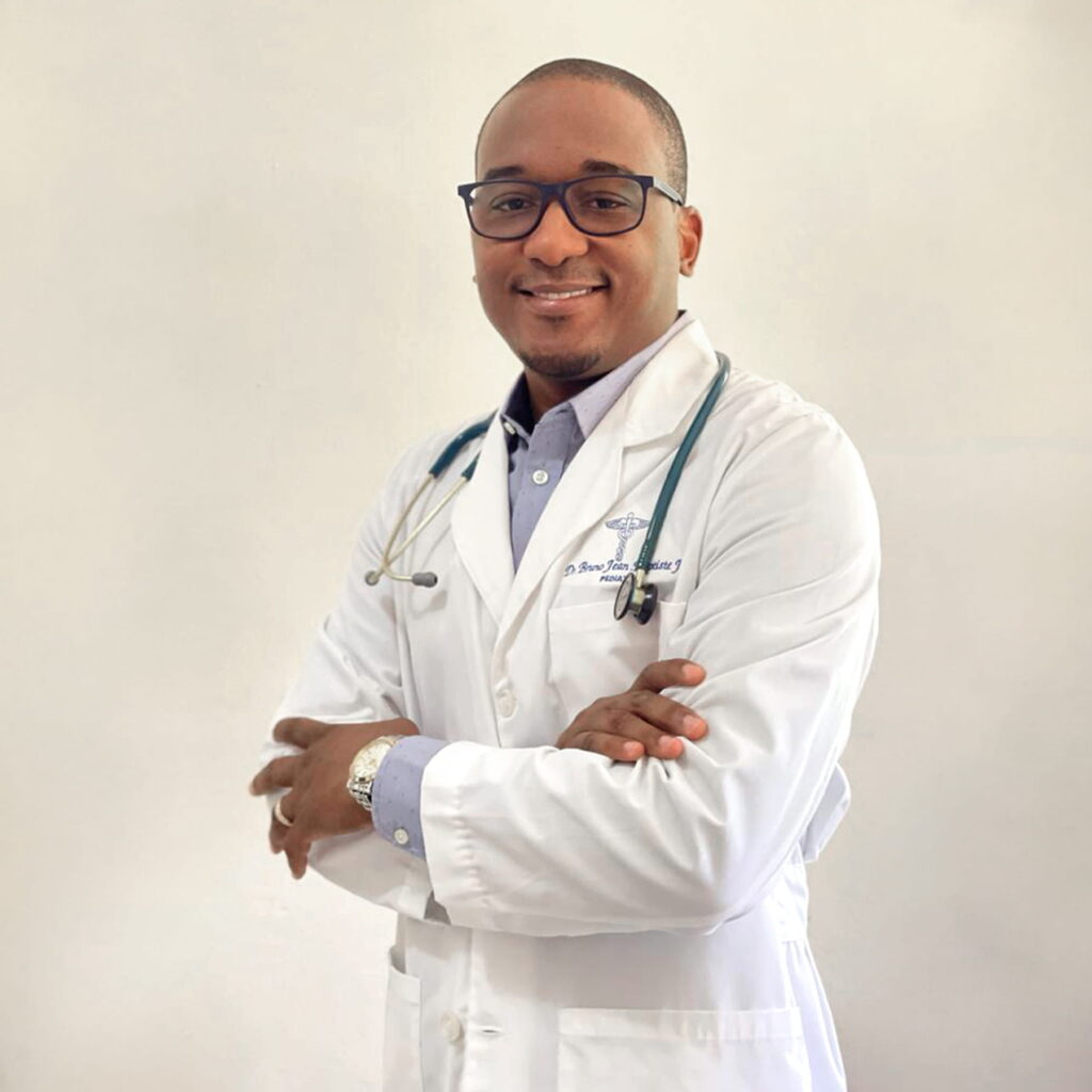 A doctor in a white coat, stethoscope around his neck, smiles at the camera.