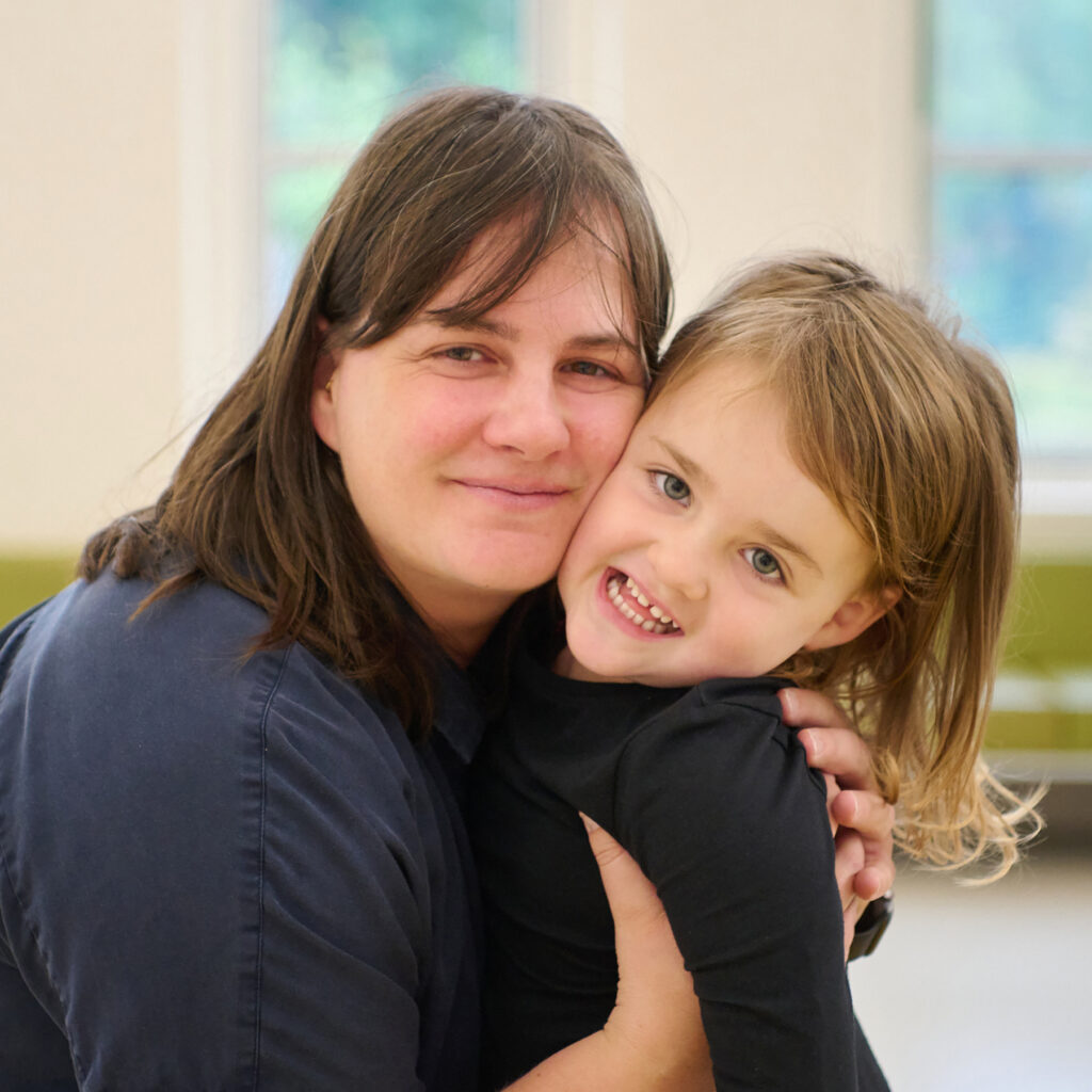 A little girl and a woman hug and smile. 