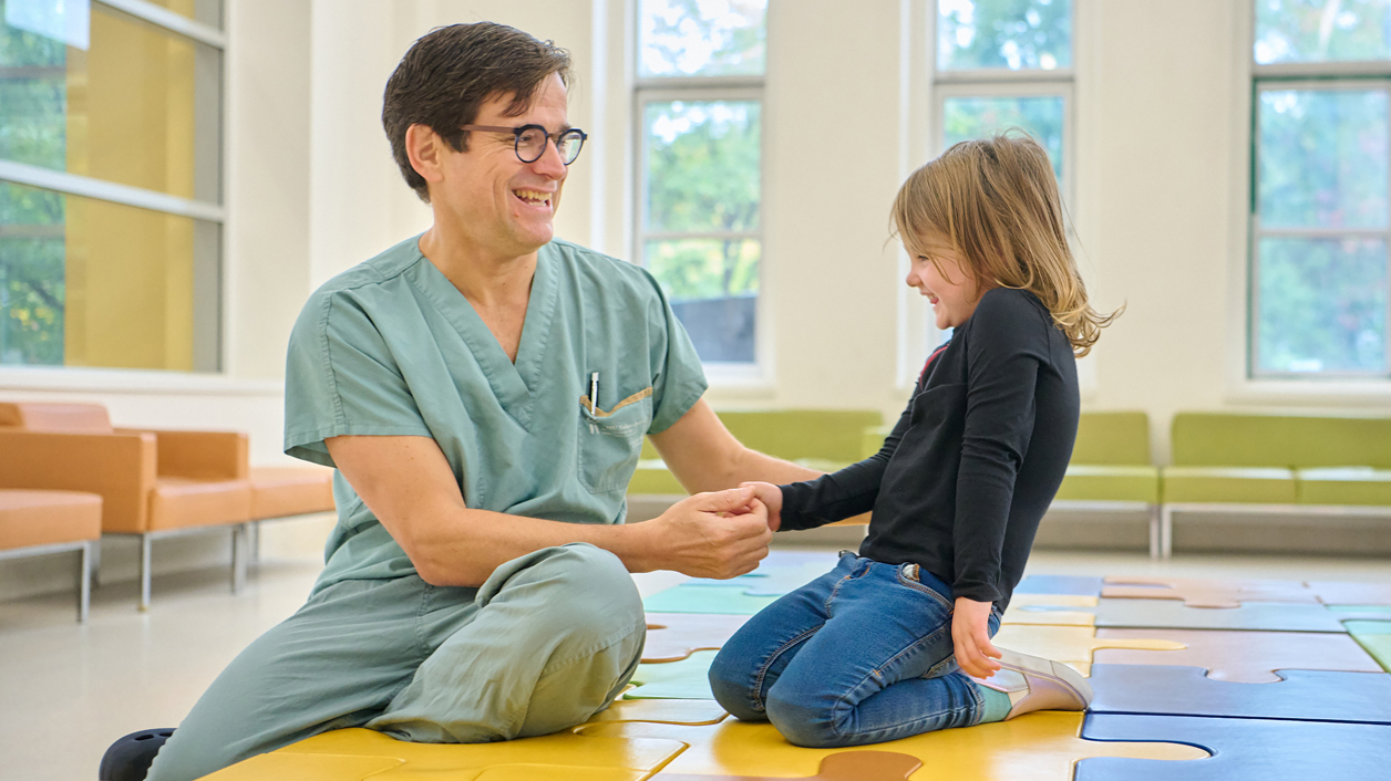 Une petite fille rit avec un homme en tenue médicale.