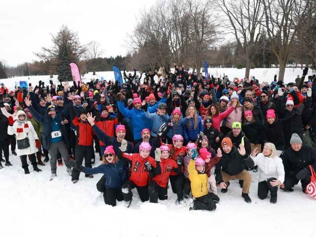 A large group looks at the camera outdoors in winter.