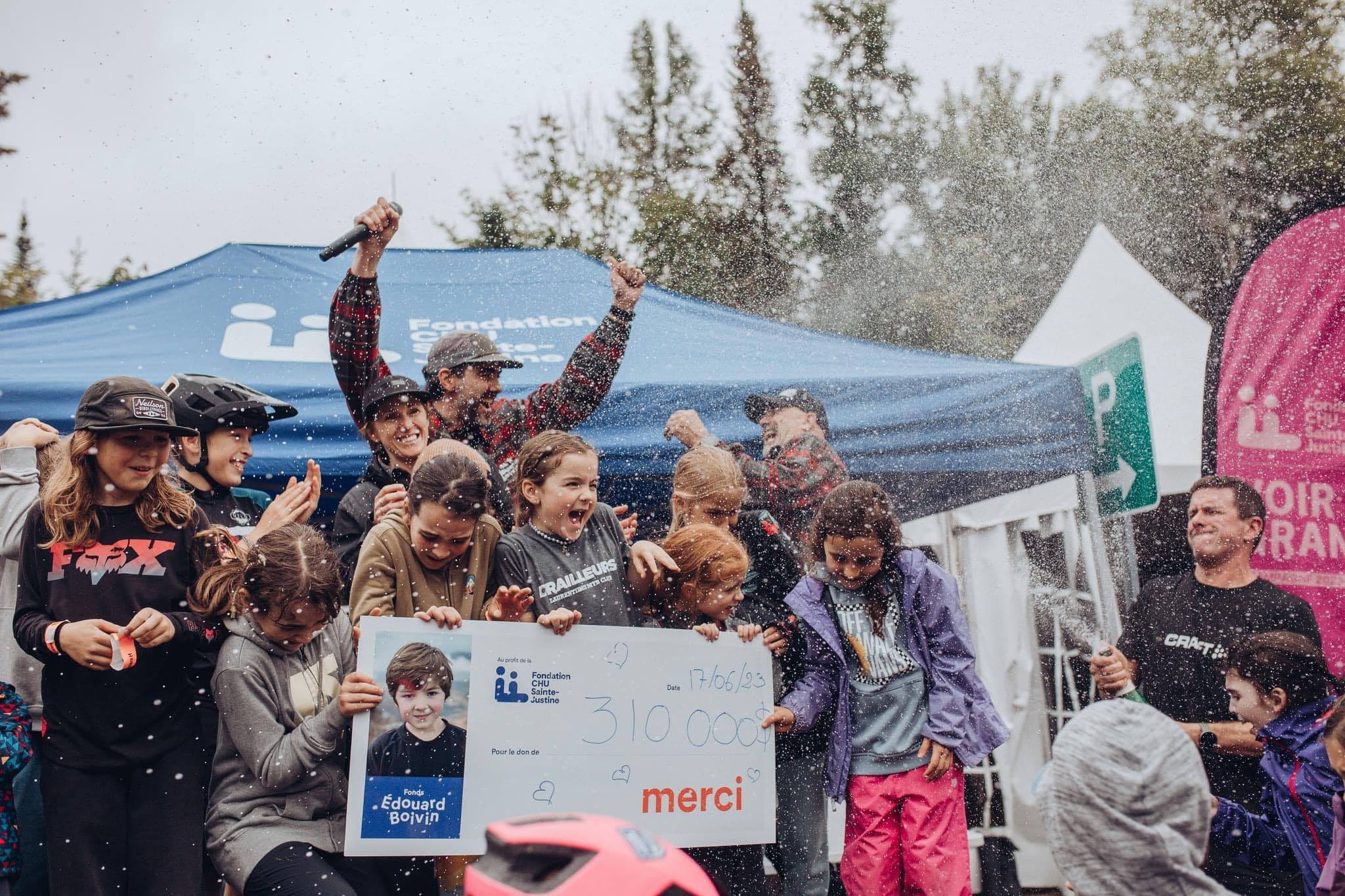 Photo de groupe c&eacute;l&eacute;brant avec des confettis et un grand ch&egrave;que devant une tente de la Fondation CHU Sainte-Justine.