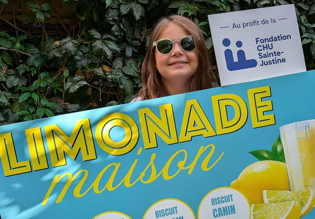Personne tenant une pancarte &laquo; Limonade maison &raquo; en soutien &agrave; la Fondation CHU Sainte-Justine.