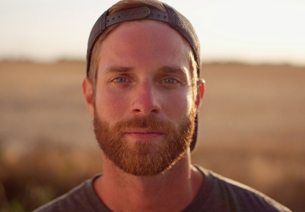 Portrait rapproch&eacute; d&rsquo;un homme portant une casquette, en ext&eacute;rieur au lever du soleil.