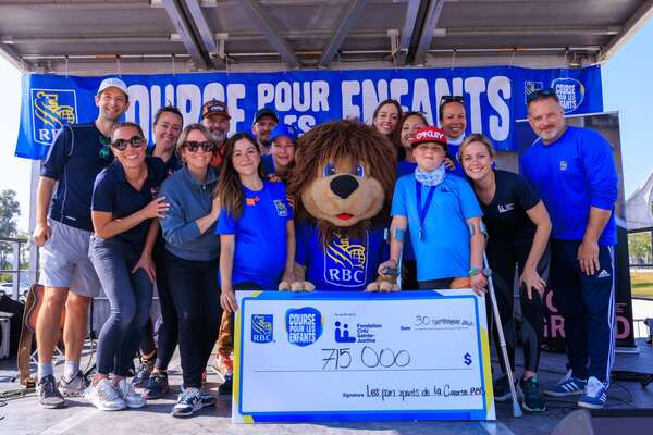 Des représentants de RBC et de la Fondation CHU Sainte-Justine, ainsi que l'ambassadeur de la Course pour les enfants RBC et la mascotte de RBC, se tiennent souriants derrière un chèque de 715 000 $